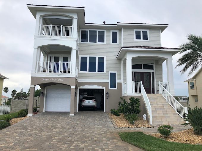 Gray and white coastal home with balconies, railings and painted siding